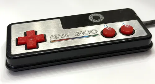 Atari 2600 gamepad with foil metal plate and red D-pad and buttons. Angle view.