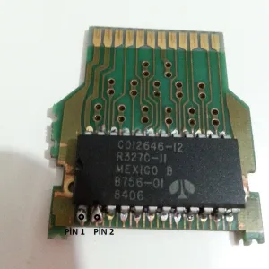A photo of the same Pac-Man PCB and ROM chip that has the two pins in question marked with text to highlight their location.