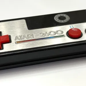 Atari 2600 gamepad with foil metal plate and red D-pad and buttons. Angle view.
